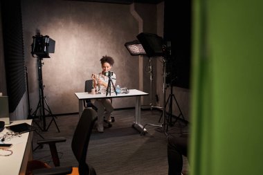 Kadın blogcu akıllı telefon kamerasının önünde oturmuş makyajdan bahsediyor.