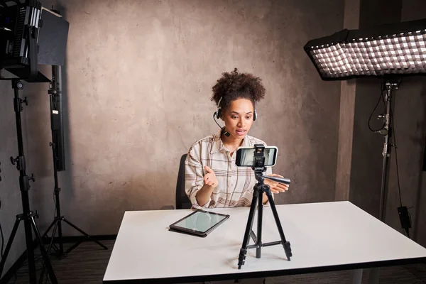 Giovane donna blogger razza mista con i capelli ricci guardando la webcam e parlando con la fotocamera — Foto Stock
