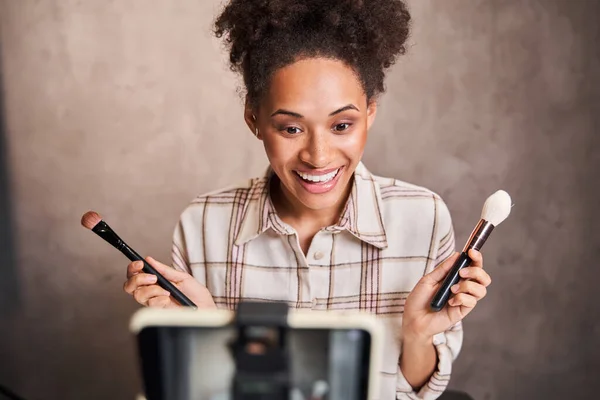 Excited multiracial woman showing two different brushes to the camera — Stock Photo, Image