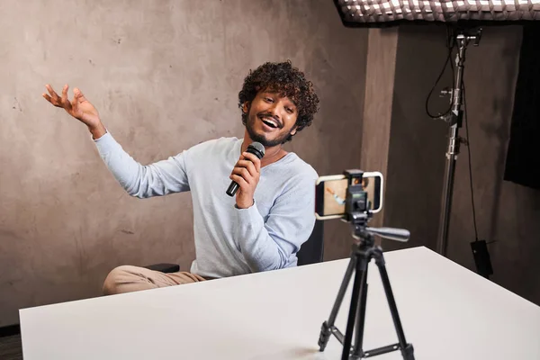Bel blogger multirazziale che canta nel suo studio al microfono — Foto Stock
