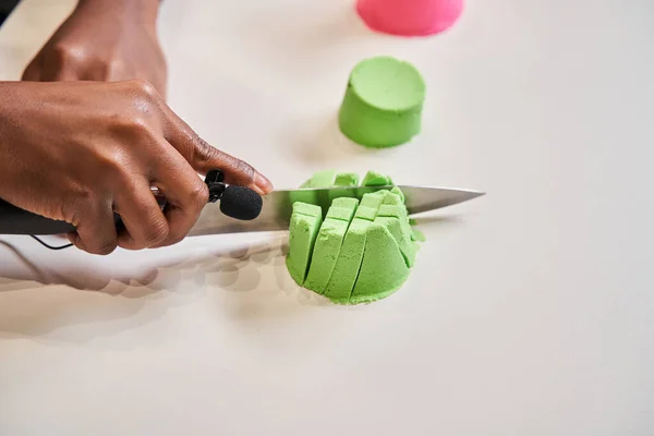 Hombre blogger cortando moldes de arena cinética con el cuchillo y grabando el sonido —  Fotos de Stock