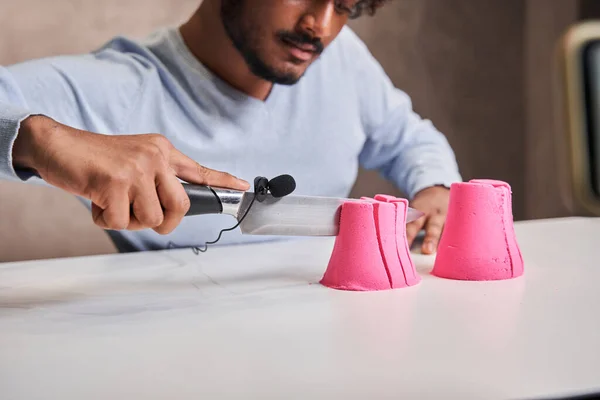 Un homme tenant un couteau avec microphone et enregistrement sonore tout en coupant du sable cinétique — Photo