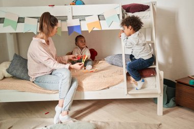 Bekar beyaz anne, evde yatağında otururken iki komik oğluyla oynuyor.