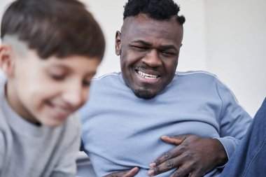 Oğlunun hafta sonu evde çizimlerine bakarken dişleri fırıl fırıl gülümseyen çok kültürlü bir adam.