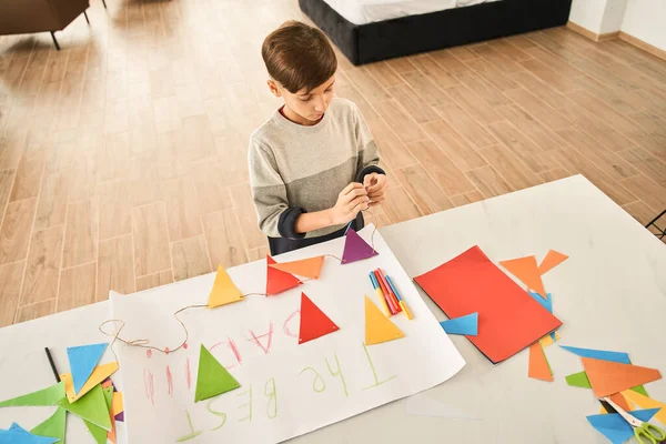 Beyaz çocuk, Babalar Günü için dekore edilmiş bir evde kağıttan çelenk hazırlıyor. — Stok fotoğraf