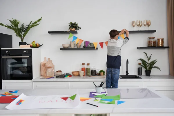 Хлопчик прикрашає квартиру з садом з кольорового паперу під час підготовки до Дня отців. — стокове фото