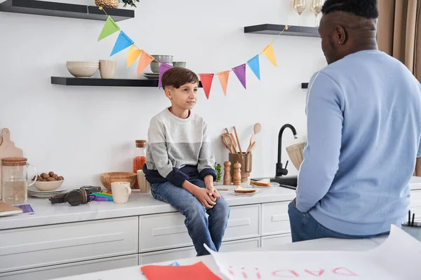 Pequeño chico caucásico y su padre multirracial hablando entre sí — Foto de Stock