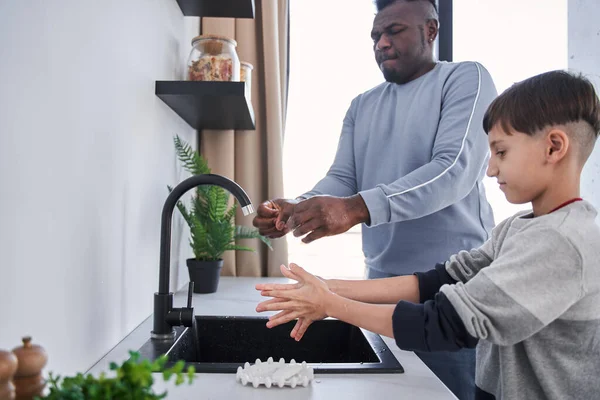 Багаторасовий батько і кавказький син миє руки на кухні — стокове фото