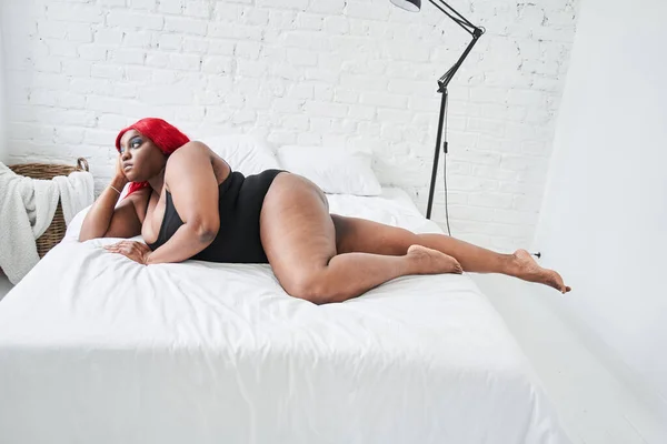 Porträtt av vackra unga multiracial kvinna i underkläder liggande och avkopplande på vit säng hemma — Stockfoto
