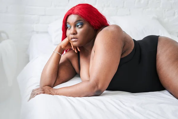 Kvinna i svarta underkläder med tillfredsställelse i ansiktet accepterar kurvig kroppsform när du lägger — Stockfoto
