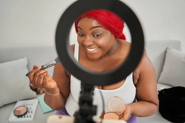 Narablog wanita multirasial sedang mempersiapkan diri dan menggunakan kosmetik di depan smartphone — Stok Foto