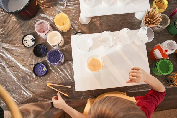 Niño poniendo pinceles en la mesa mientras prepara el dibujo con diferentes pinturas — Foto de Stock