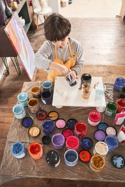 Caucásico morena chico recogiendo pintura en sus manos mientras dibujo en la escuela de arte —  Fotos de Stock