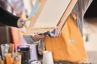 Sanat okulunda resim yaparken üzerinde yeni boyalar akan önlük taşıyan bir çocuk.