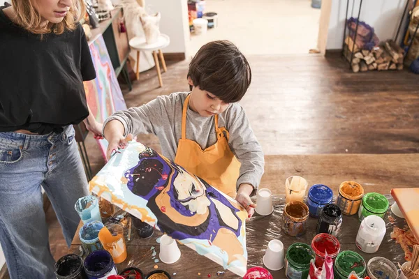 Malý chlapec drží abstraktní malba provedena v tekuté umění techniky, zatímco kreslení se svým učitelem — Stock fotografie