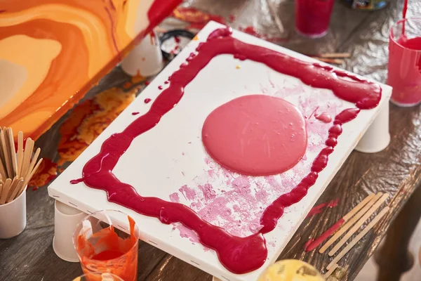 Pinturas rojas y rosadas húmedas frescas vivas en la obra maestra de dibujo abstracto que se coloca en la mesa —  Fotos de Stock