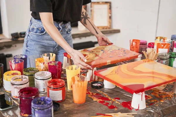 Artista femenina sosteniendo mojado de pinturas de lona y mirándolo mientras terminaba sus dibujos —  Fotos de Stock