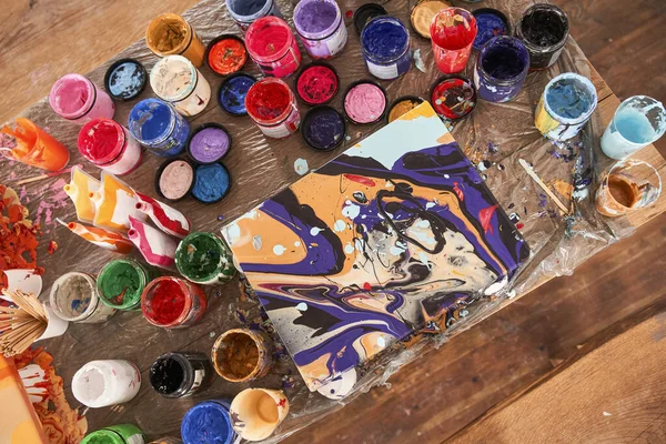 Vista superior de la mesa de madera y pintura abstracta colocada sobre ella —  Fotos de Stock