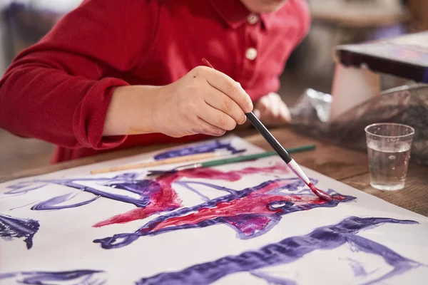 Beyaz çocuk kağıda fırça ve akrilik boyalarla balık çiziyor. — Stok fotoğraf