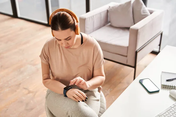 Caucasian girl with prosthesis hand typing on smartwatch while working at home