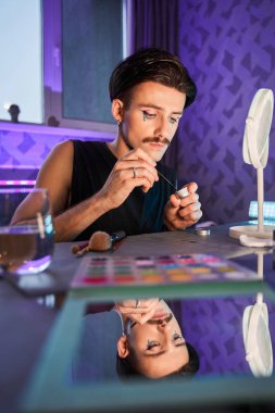 Adam kavanozdan pulları alırken aynanın önünde muhteşem bir makyaj yapıyor.
