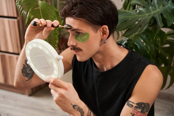 Guy v domácím oblečení pomocí oční pásky při masáži obličeje s nefritovým válečkem — Stock fotografie