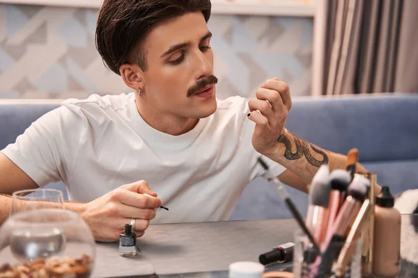 Przystojny facet z wąsami dmuchanie w jego paznokcie podczas dokonywania modny manicure — Zdjęcie stockowe