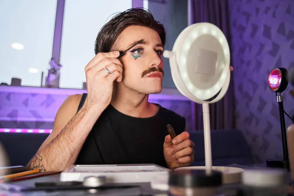 Biały mężczyzna z kreatywnym makijażem z brokatami patrzący w lustro na odbicie — Zdjęcie stockowe