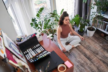 Nilüfer pozisyonunda oturan sakin kadın, meditasyon yapıyor ve yoga yapıyor.