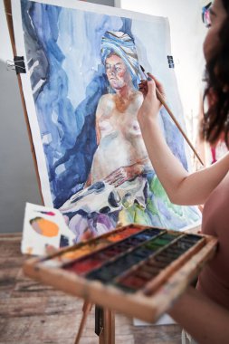 Resim sehpası, boya fırçası ve palet tablosu olan kadın sanatçı.