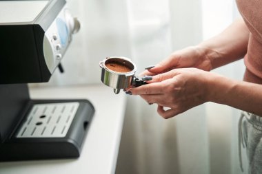 Mutfakta sabah içkisini hazırlarken elinde öğütülmüş kahveyle gezen kadın.
