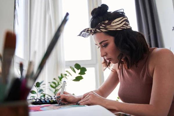 Designer gráfica feminina concentrada usando marcadores enquanto trabalhava em sua nova obra de arte no notebook — Fotografia de Stock