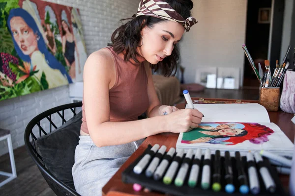 Umělkyně tvůrčí návrhářka nebo ilustrátorka sedí u stolu a kreslí své nové umělecké dílo — Stock fotografie