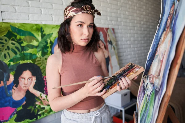 Artista feminina pintando sobre tela com tintas aquarela enquanto trabalhava em sua pintura em casa — Fotografia de Stock