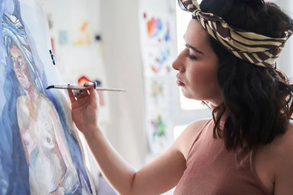 Žena drží štětec při malování obrazu na stojanu ve svém světelném výtvarném studiu — Stock fotografie