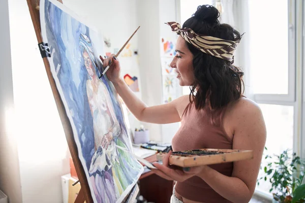 Yaratıcı, güzel, profesyonel kadın ressam oturma odasında resim yaparken, sehpanın önünde duruyor. — Stok fotoğraf