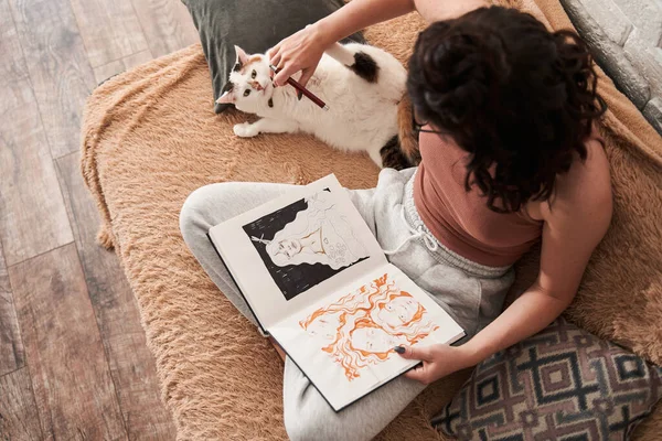Női művész játszik macska, miközben rajzol a notebook otthonról — Stock Fotó