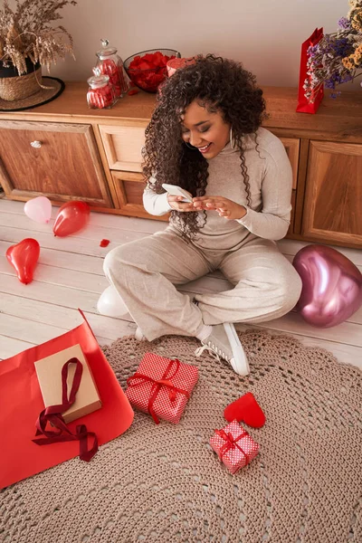 多人種の女性は鮮やかなリボンでスタイリッシュな赤い紙に包装した後、彼女のプレゼントを撮影 — ストック写真