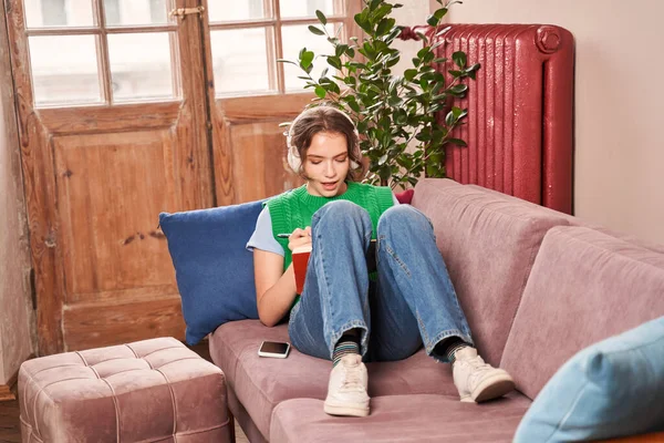 Ruhiges Teenie-Mädchen mit Kopfhörern entspannt sich auf dem Sofa und hört Musik — Stockfoto