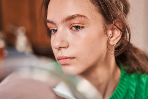 Подросток с желтыми веками, смотрящий на зеркало с довольной улыбкой