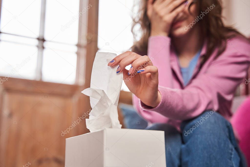 Depressed teen girl taking napkin while crying at the psychologist office