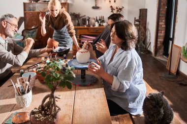 Yaşlılar öğretmenlerini dinlerken kil ve jöleden ürünler yapıyorlar.