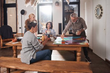 Olgun bir adam kendi şaheserini yaratırken tuvale yeni boyalar koyar.