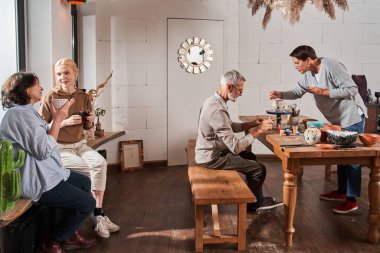Masada oturan ve el yapımı çaydanlıklar yapan iki emekli.