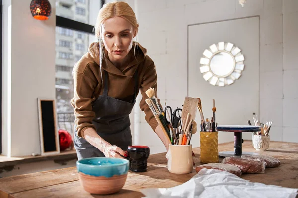 Femme préparant son lieu de travail tout en mettant différentes choses à la table avec un visage concentré — Photo