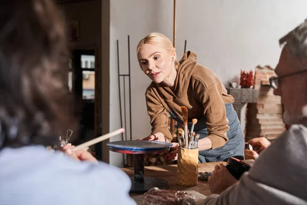 Female teacher explaining something to the mature people while they sitting at the master class — Stock Photo, Image