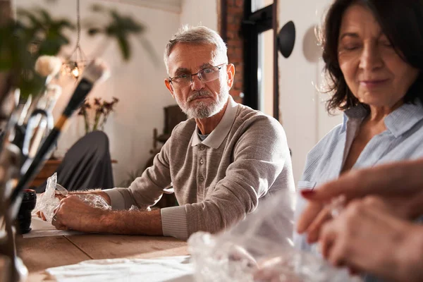 Grey haired bearded man looking with concentrated face at the teacher — Stock Photo, Image