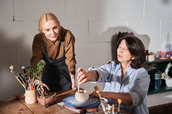 Bella signora bruna che fa vaso di argilla in laboratorio di ceramica — Foto Stock