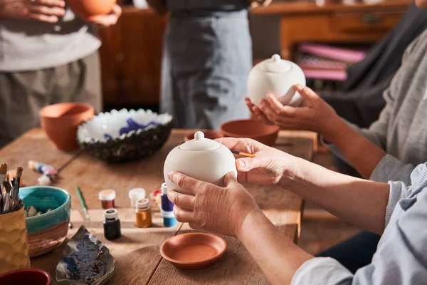 Mature ladies holding clay teapots and preparing to glaze it at their own taste — Photo