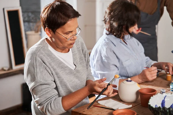 Yaşlı kadın atölyedeki kilden yemek yapıyor.